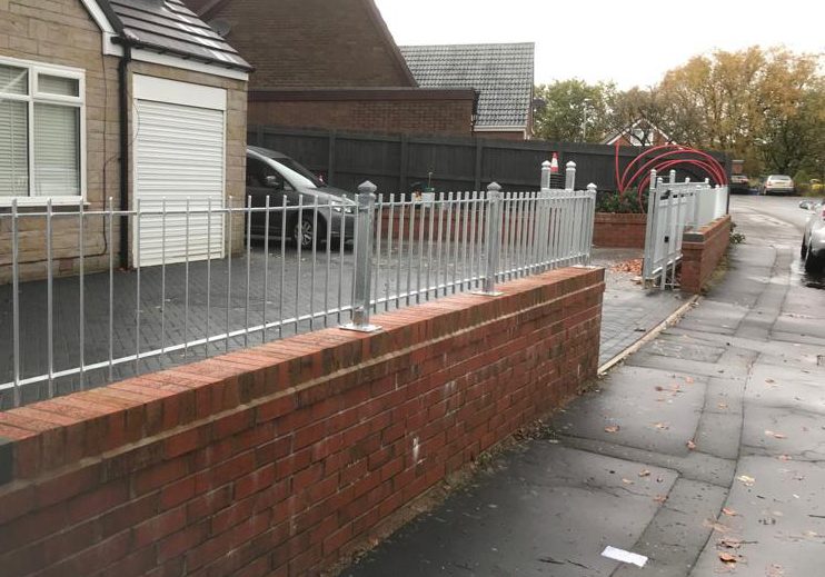 Iron railings on top of a brick wall surrounding a house